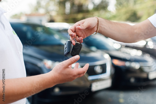 The owner of a new car getting the keys from the hands of the car dealer