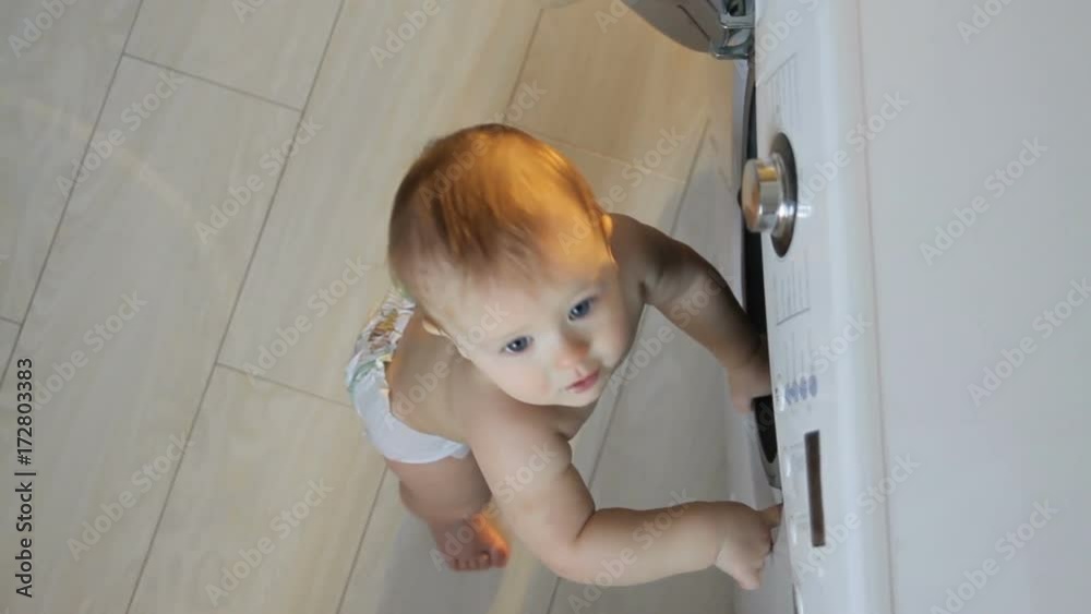 Baby boy next to washing machine Baby boy next to washing machine