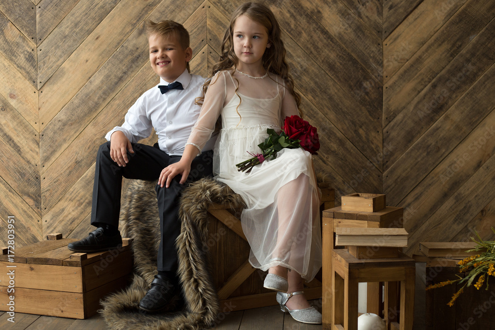 Fototapeta premium Boy and girl, brother and sister, friends with a bouquet of flowers in a beautiful studio. Childhood, friendship, porter.