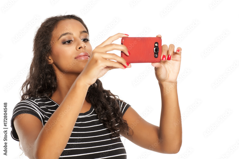 Young and happy dark skinned girl taking photos with her smartphone Young and happy dark skinned girl taking photos with her smartphone