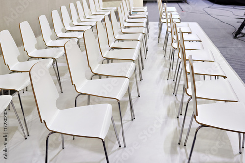 Rows of white chairs in presentation room © Sergey Ryzhov