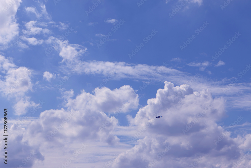 The helicopter Fly in bright blue sky with a big white clouds on a beautiful day The helicopter Fly in bright blue sky with a big white clouds on a beautiful day
