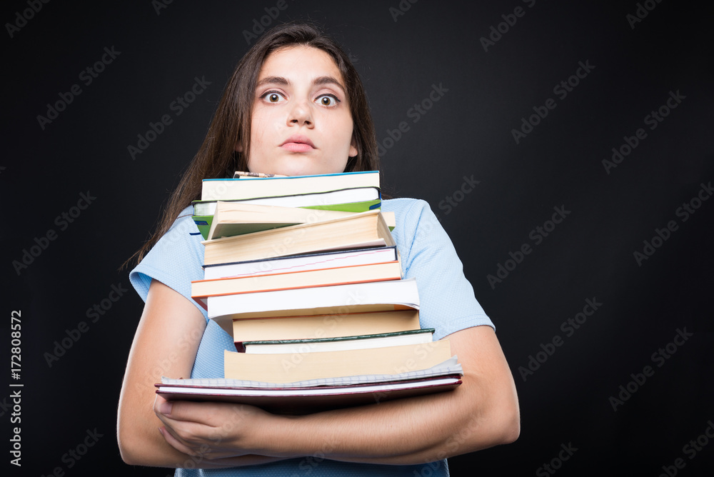 Sad college student carrying a stack of books Sad college student carrying a stack of books