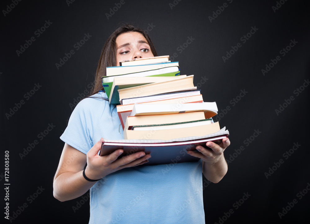 Young girl carrying heavy pile of books