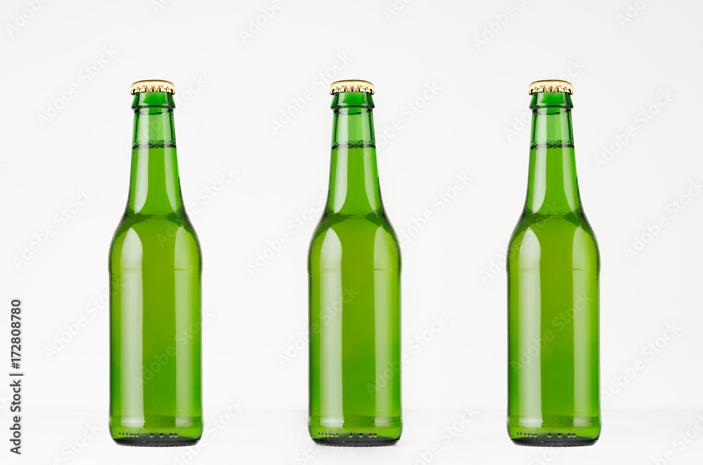 Three green longneck beer bottles 330ml, mock up. Template for advertising, design, branding identity on white wood table. Three green longneck beer bottles 330ml, mock up. Template for advertising, design, branding identity on white wood table.