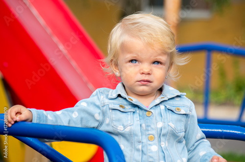 Portrait of a blonde girl with blue eyes on a playground