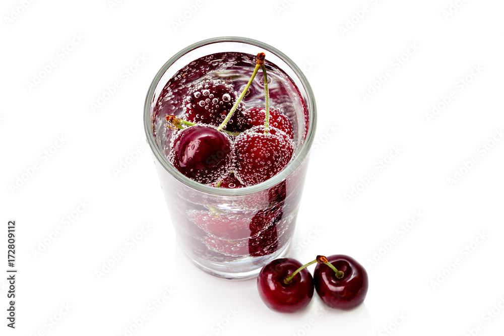 Cherries in a transparent glass with sparkling water isolated on white background. View from above Cherries in a transparent glass with sparkling water isolated on white background. View from above