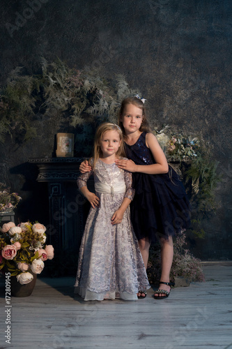 Two girls, sisters. girlfriend, model in a beautiful studio with flowers. Portrait, childhood, fashion.