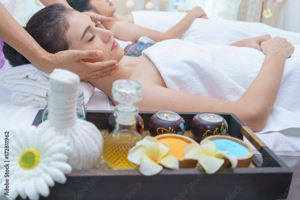 Beautiful young Asian woman relaxing , lying on massage table and having Thai traditional face massage in spa salon Beautiful young Asian woman relaxing , lying on massage table and having Thai traditional face massage in spa salon