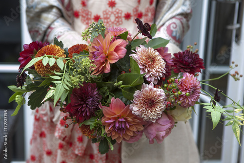 Fototapeta Naklejka Na Ścianę i Meble -  bride in a red lace dress holds a bouquet of dahlias and roses