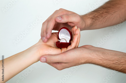 female and male hands holding the ring box