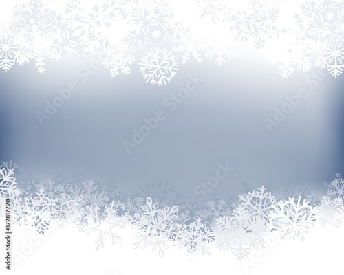 Winter background. White  border made of fluffy snowflakes with space for text on soft blue background .