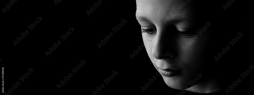 The sad boy with tears in their eyes on a black background