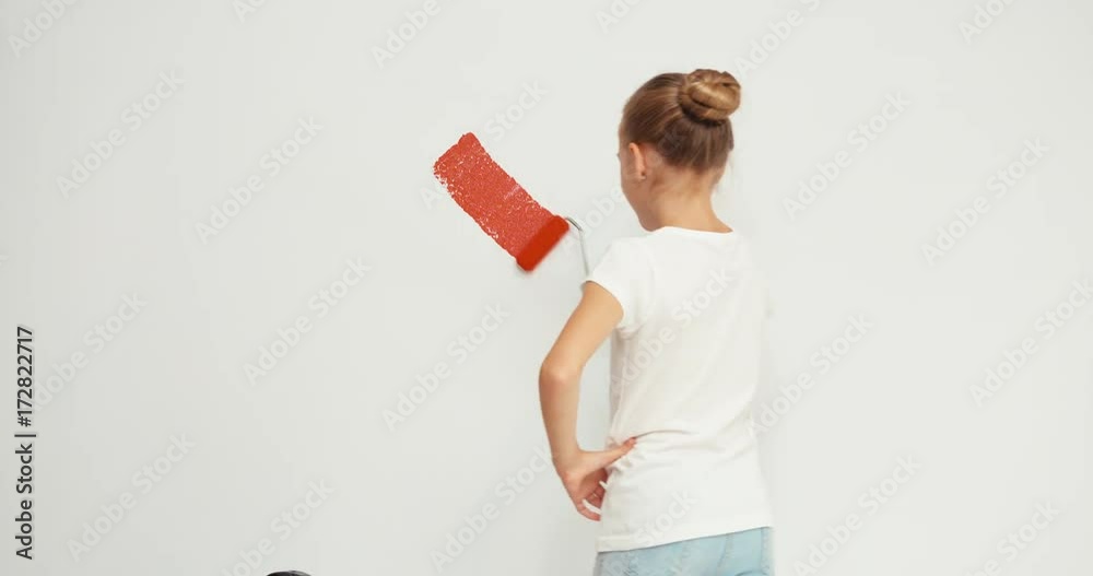 Child girl starting painting red heart on the wall Child girl starting painting red heart on the wall