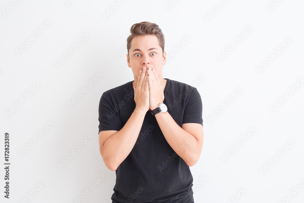 handsome man in black t shirt on white background showing scared emotion and close hands mouth handsome man in black t shirt on white background showing scared emotion and close hands mouth