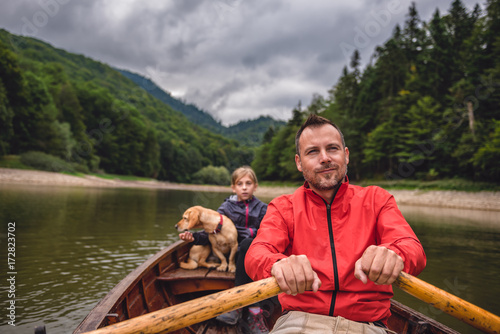 Father and daughter with a dog rowing a boat