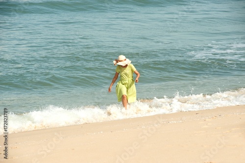 Beautiful happy multiracial Asian girl in vintage dresses walking on the beach.