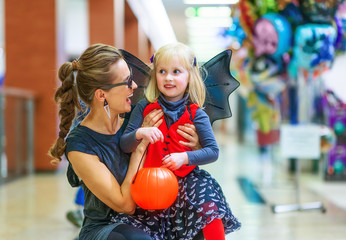 smiling elegant mother and daughter on Halloween at mall