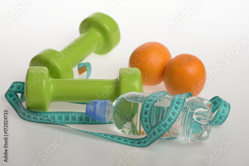 Dumbbells in green color, water bottle, measure tape and fruit
