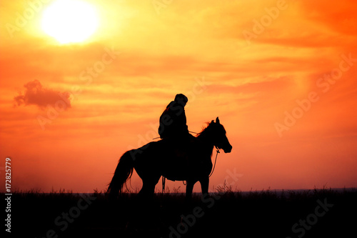 фотографія rider on horseback in a steppe during colorful sunset, Kazakhstan