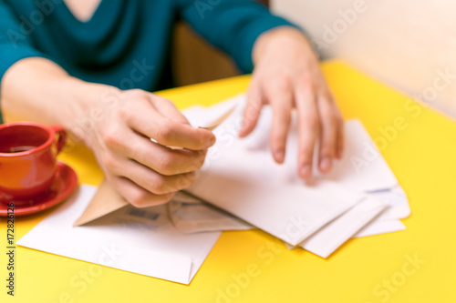 A man sorts the mail. Male hands the envelopes on a yellow background, a red coffee Cup.