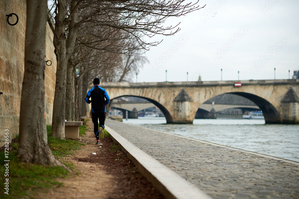 Man running along the banks of Seine river in Paris