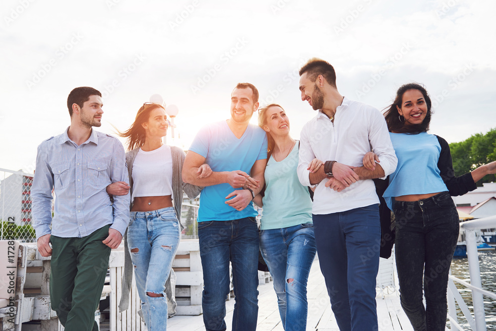 Smiling happy group of friends posing for the camera outdoors on the beach pier