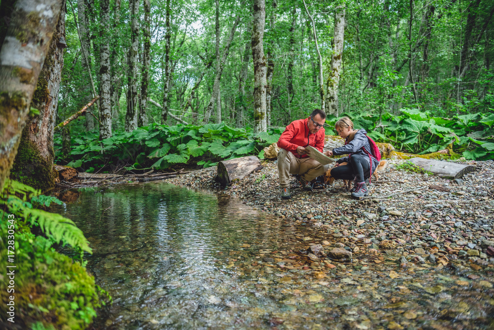 Father and daughter hiking in forest and checking map Father and daughter hiking in forest and checking map