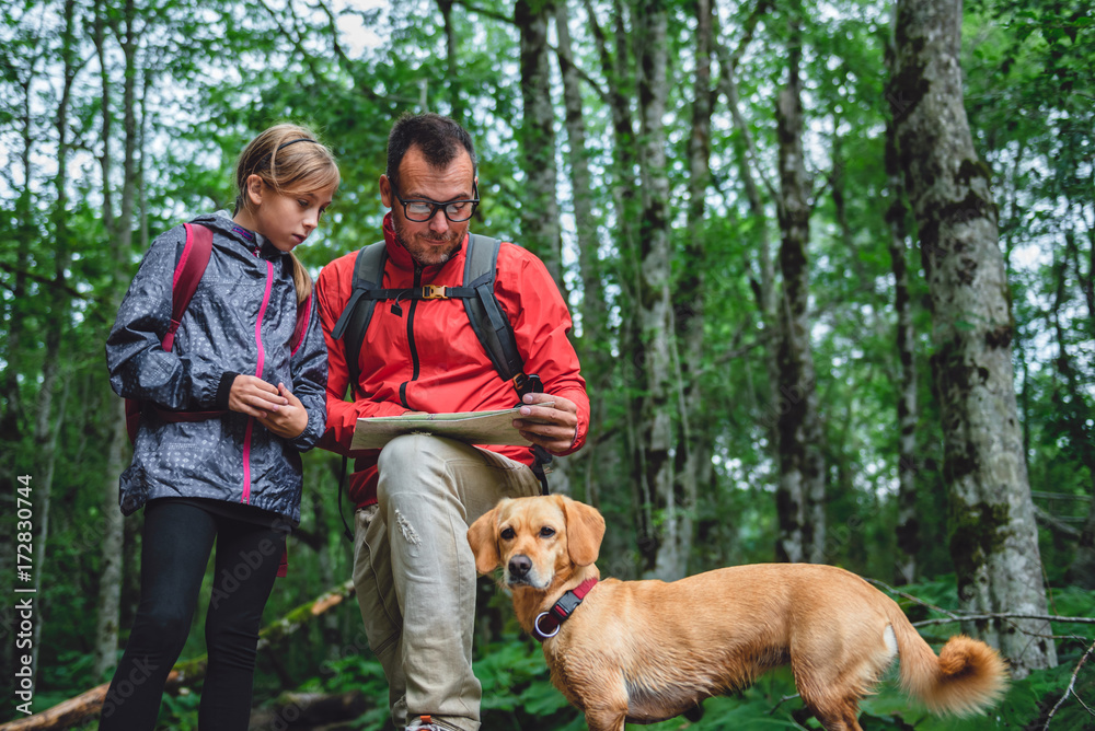 Father and daughter hiking in forest and checking map Father and daughter hiking in forest and checking map