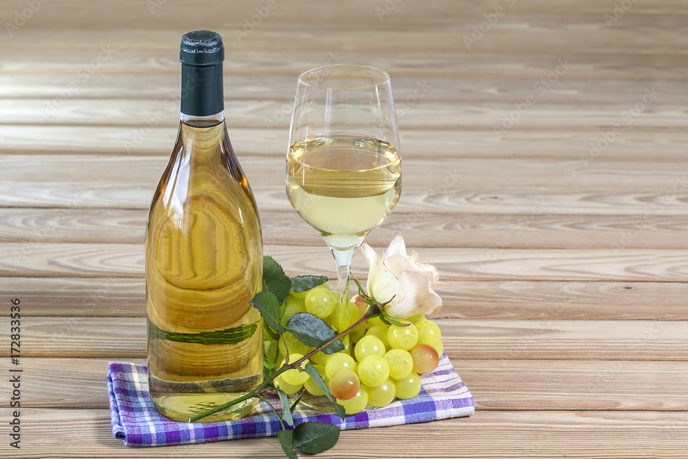 Bottle and glass of white wine are stand on table together with rose Bottle and glass of white wine are stand on table together with rose
