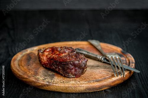 Barbecue Dry aged Ribeye Steak with knife and fork on cutting board photo