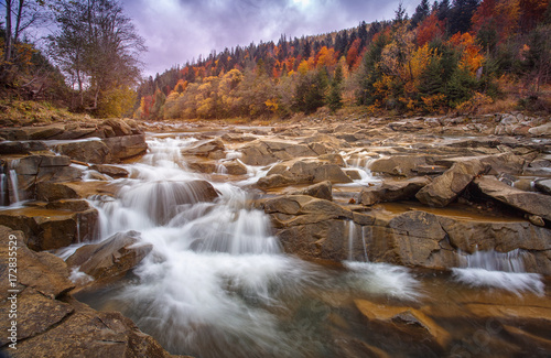 Restless dangerous mountain river with stones. The river in the autumn forest