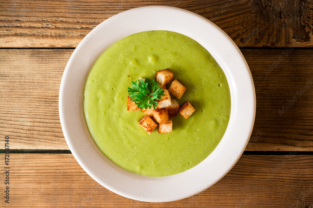 Broccoli cream soup with croutons in plate on rustic wooden table Broccoli cream soup with croutons in plate on rustic wooden table