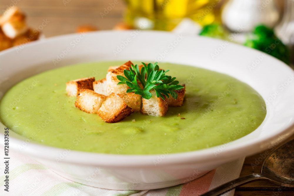 Broccoli cream soup with croutons in plate on rustic wooden table Broccoli cream soup with croutons in plate on rustic wooden table