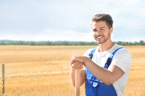 Young male farmer standing with shovel in field