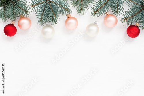 New Year`s card. Red, white balls, blue spruce branches on the top of white wooden texture, copy space.