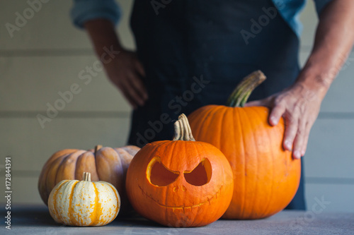 Man standing behind bunch of pumpkins for halloween photo