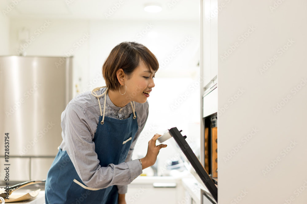 オーブンを開ける若い女性 オーブンを開ける若い女性