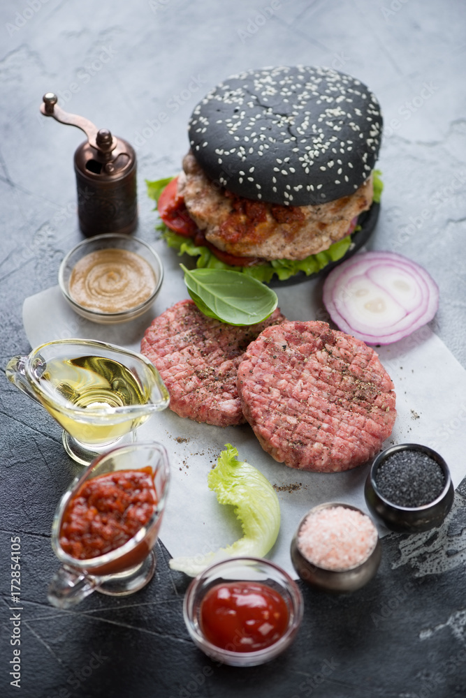Raw burger cutlets, black hamburger and cooking components. Selective focus, vertical shot Raw burger cutlets, black hamburger and cooking components. Selective focus, vertical shot