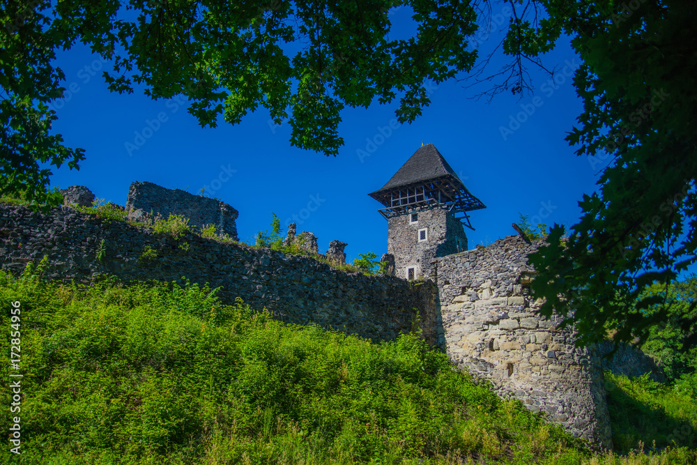 Fototapeta premium Stone fortification on green hill on blue sky