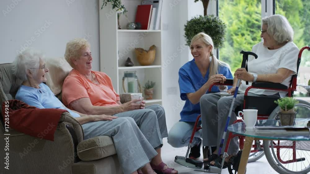 Caring nurse taking care of and talking to elderly residents in a retirement home.