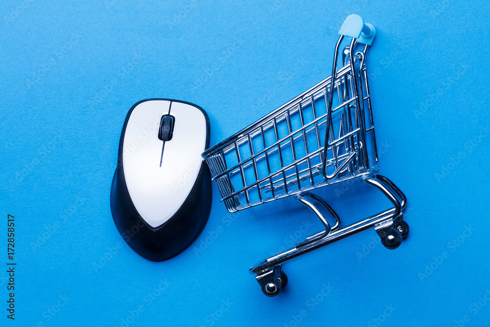 Fotografie Shopping cart on a blue background with computer mouse