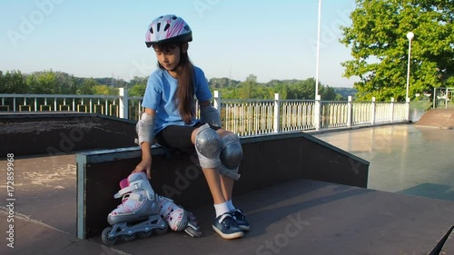 A child is putting on a roller. Little girl wearing a helmet dresses a roller skate. photo