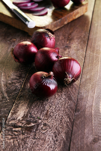 Red onions circles and red onions on board against wooden backgr