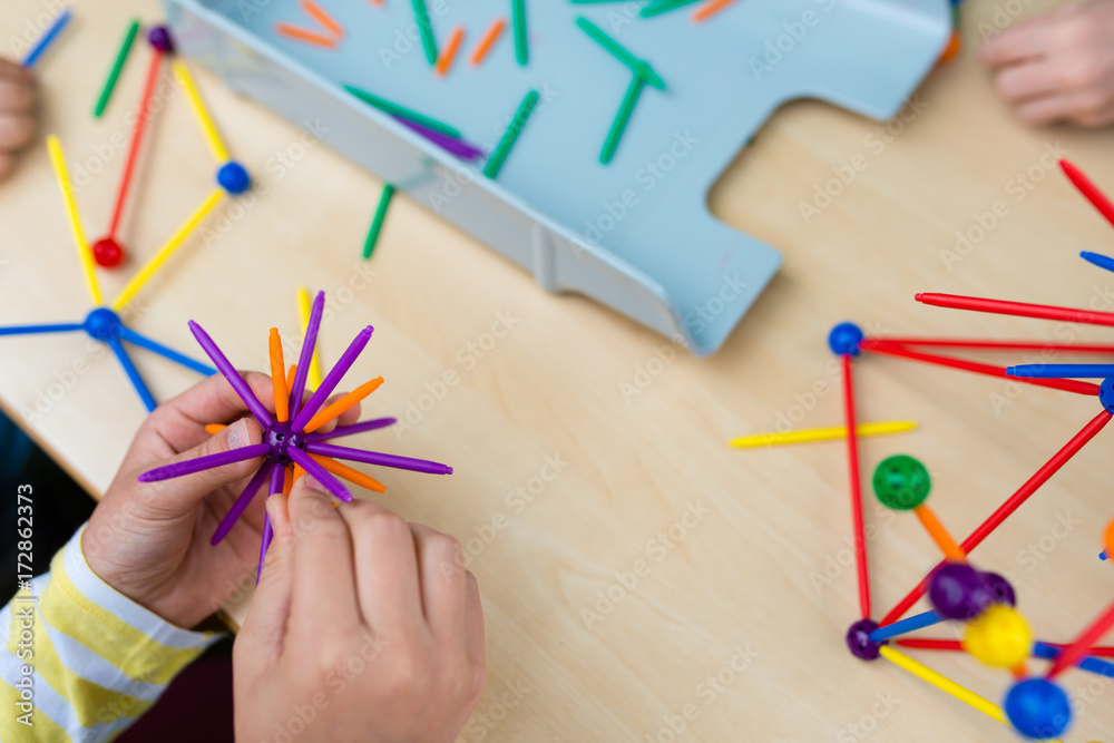 Two little girls playing with lots of colorful plastic sticks kit indoors. kids having fun with building geometric figures and learning mathematics in preschool or primary class of school Two little girls playing with lots of colorful plastic sticks kit indoors. kids having fun with building geometric figures and learning mathematics in preschool or primary class of school