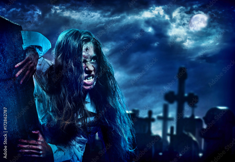 Undead zombie scary girl on halloween graveyard at night on dark clouds sky  background. Woman in zombie apocalypse hunting outdoor. Behind monster  cemetery with crosses. Moon comes out from clouds Stock Photo