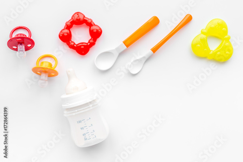 preparation of mixture baby feeding with infant formula powdered milk in bottle with bib on white background top view mockup