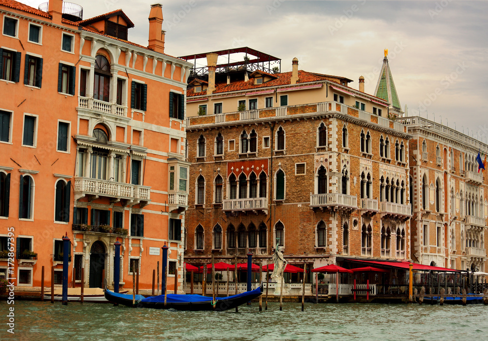 Beautiful old bright houses near the canal with gondola in Venice, Italy under blue sky