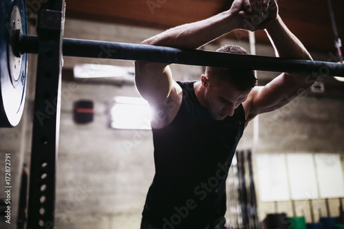 Young caucasian man recovering from lifting weights in gritty workout gym