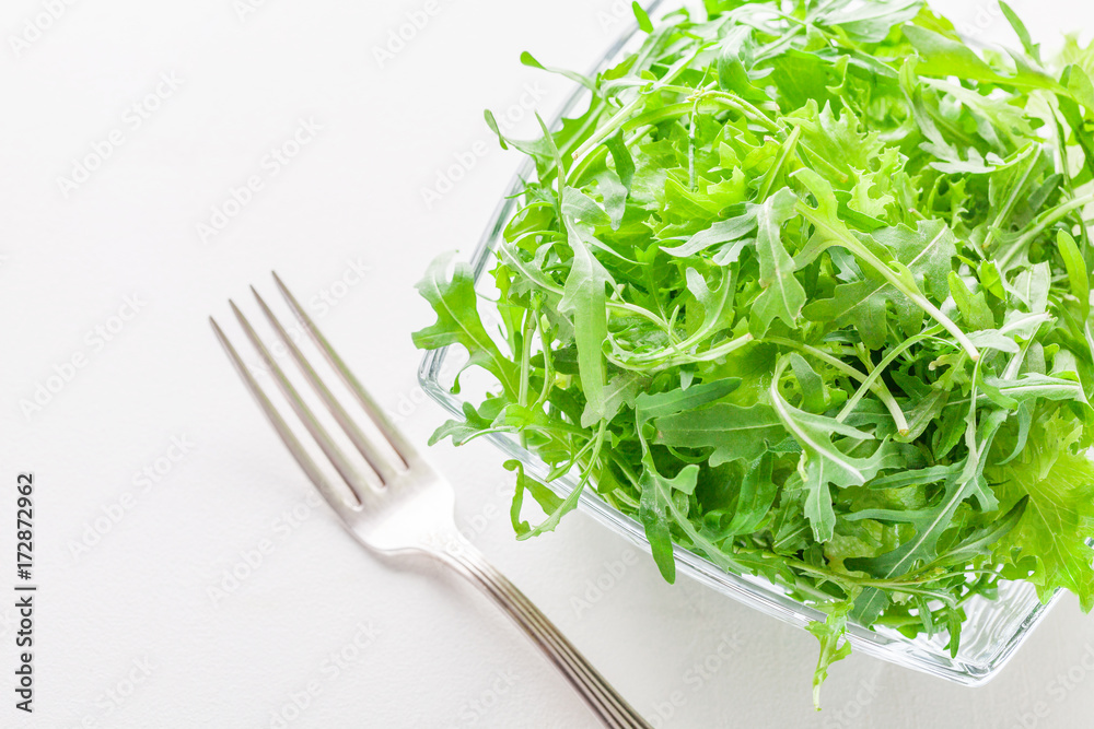 Green salad in a glass bowl on a white table Green salad in a glass bowl on a white table